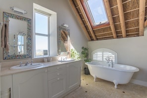 A bathroom with a large window, a bathtub, and a vanity with two sinks. - The Beach Villa (Cape Town)