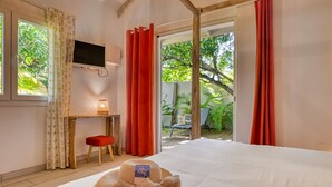 Quarto com cama, televisão fixada na parede, escrivaninha com cadeira e vista para o exterior.