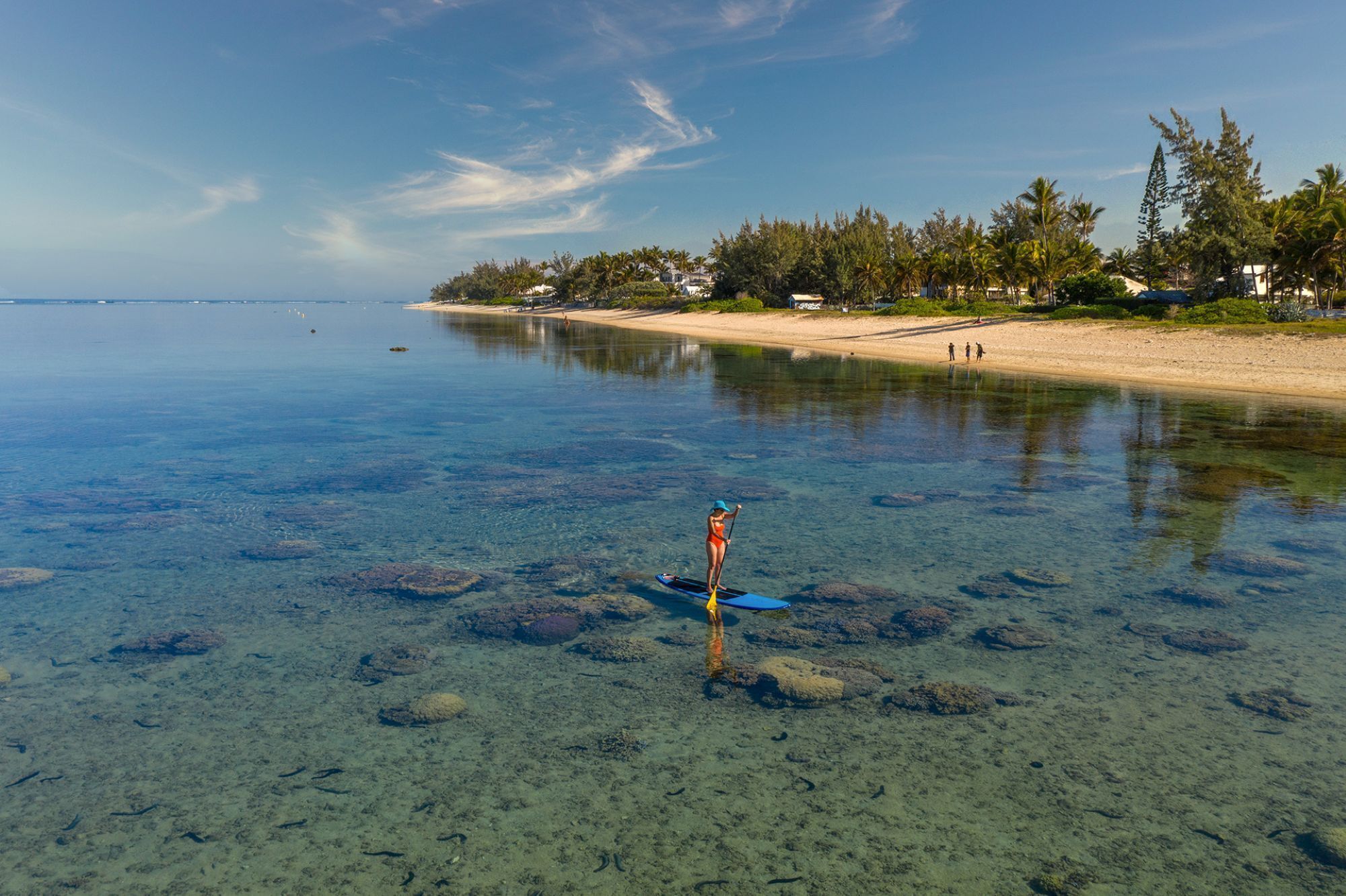 A clear view of a beach with a person paddleboarding.