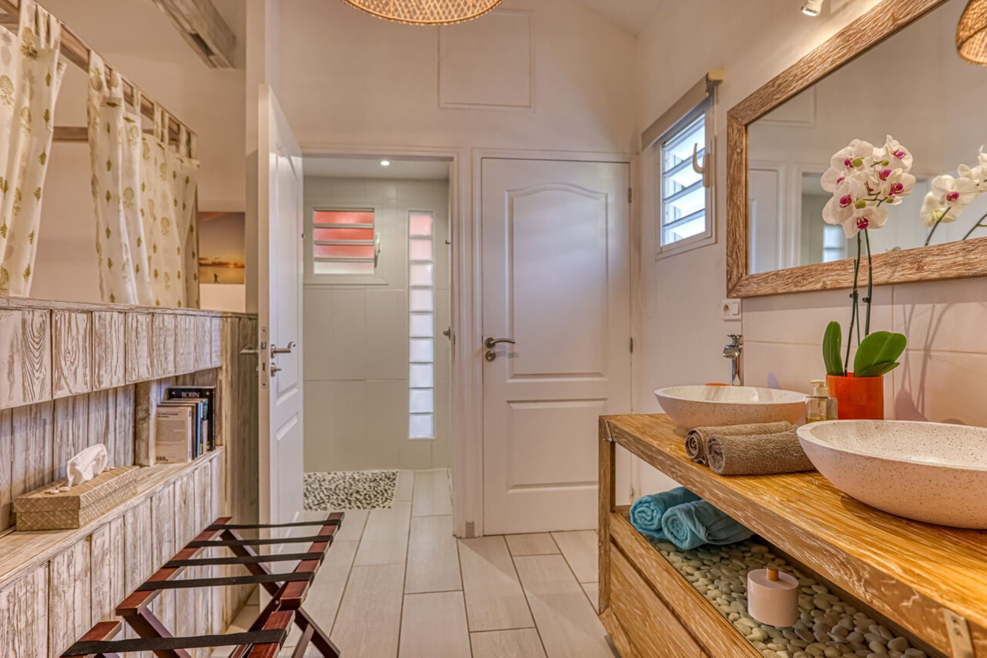 A bathroom with a wooden vanity, two sinks, a mirror, and a towel rack.
