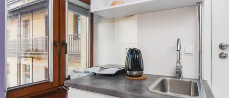 A compact kitchen with a built-in sink, a kettle, and a small countertop.