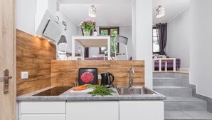 Una cocina moderna con horno integrado, un lavamanos y una zona de comedor con mesa y sillas.