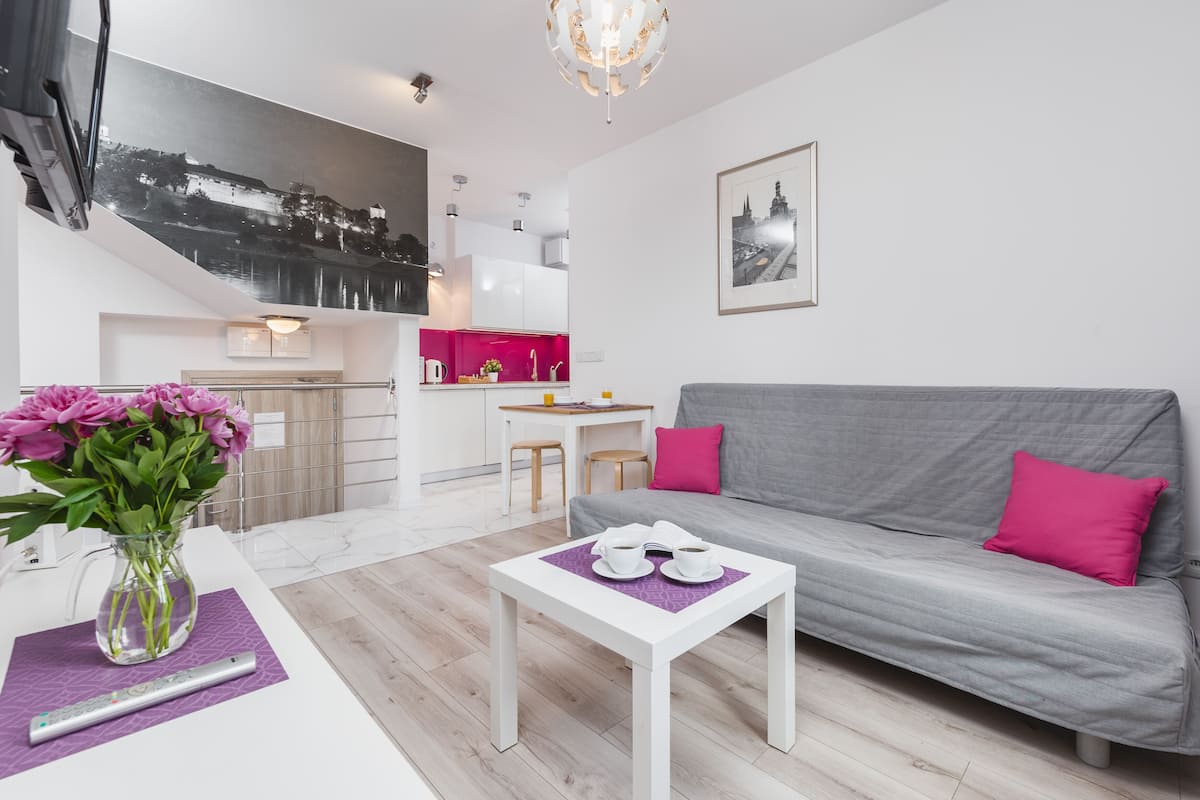 Un salon moderne avec un canapé gris, une table basse blanche et un vase de fleurs.