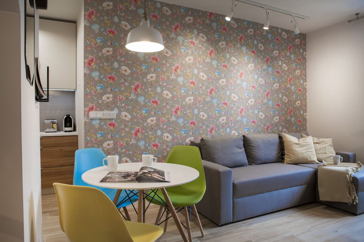 Un salon moderne avec un canapé, des fauteuils, une table et un papier peint à motifs floraux.