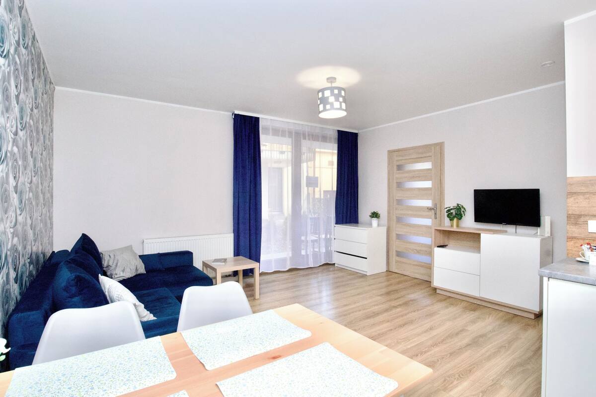 Un salon moderne comprenant un canapé, une table à manger, un téléviseur et un meuble en bois.