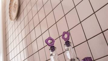 Eine Küche mit weiß gefliestem Fliesenspiegel, einem violetten Geschirrgestell und klaren Glasflaschen mit violetten Deckeln.