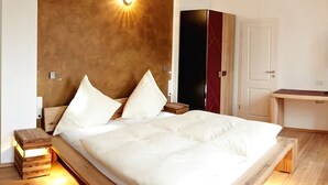 A modern bedroom with a large bed, a bedside table with a lamp, a wardrobe, and a desk with a chair. - Residenz Schloss Engers (Neuwied)