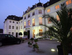 Un edificio grande y blanco con muchas ventanas y una entrada pavimentada.