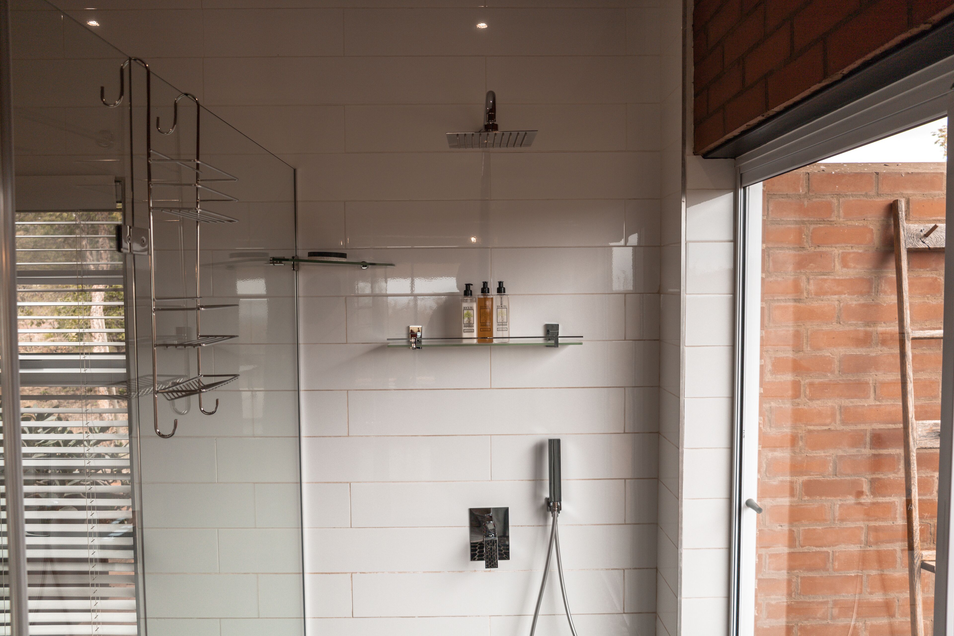 Une salle de bain moderne avec une douche à parois de verre, un porte-serviettes et une étagère contenant des articles de toilette.