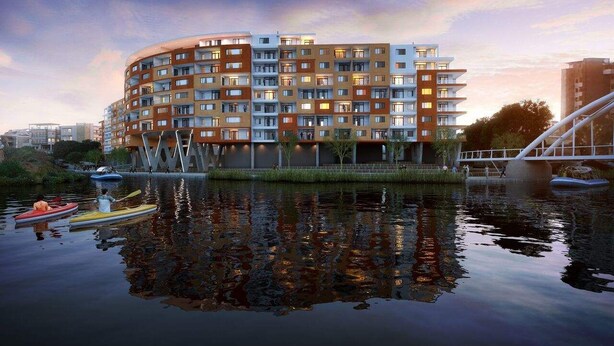 A modern multi-story building with balconies, situated by a calm body of water with kayaks. - Blou Inn - Century City (Cape Town)