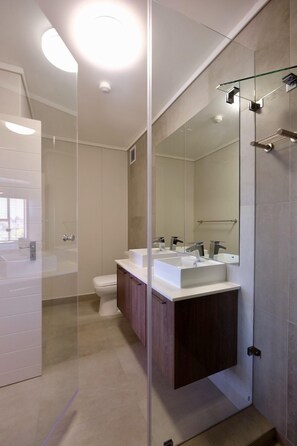 A modern bathroom with a glass shower enclosure, a large mirror, and a dual sink vanity. - Blou Inn - Century City (Cape Town)
