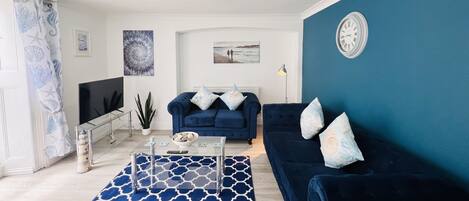 A living room with a blue sofa, a coffee table, and a patterned rug.