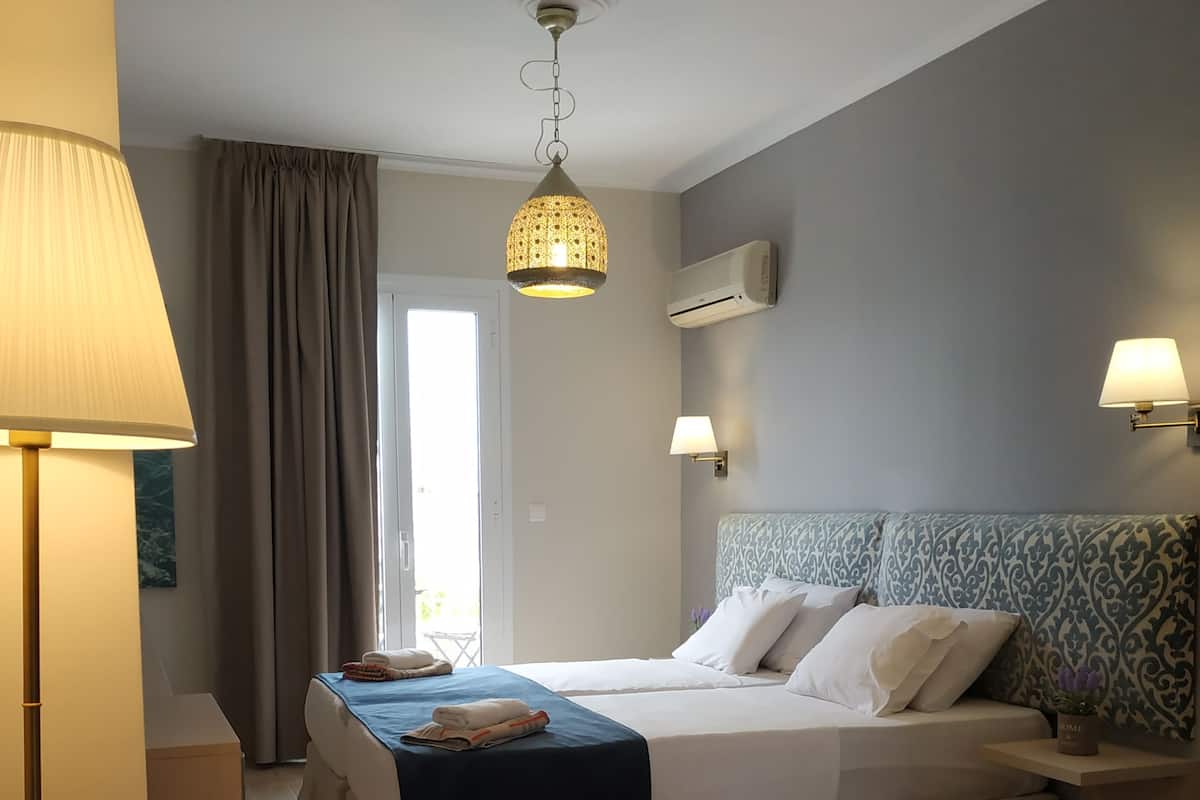 A hotel room with a bed, bedside tables, a lamp, a chair, and a view of the outdoors.