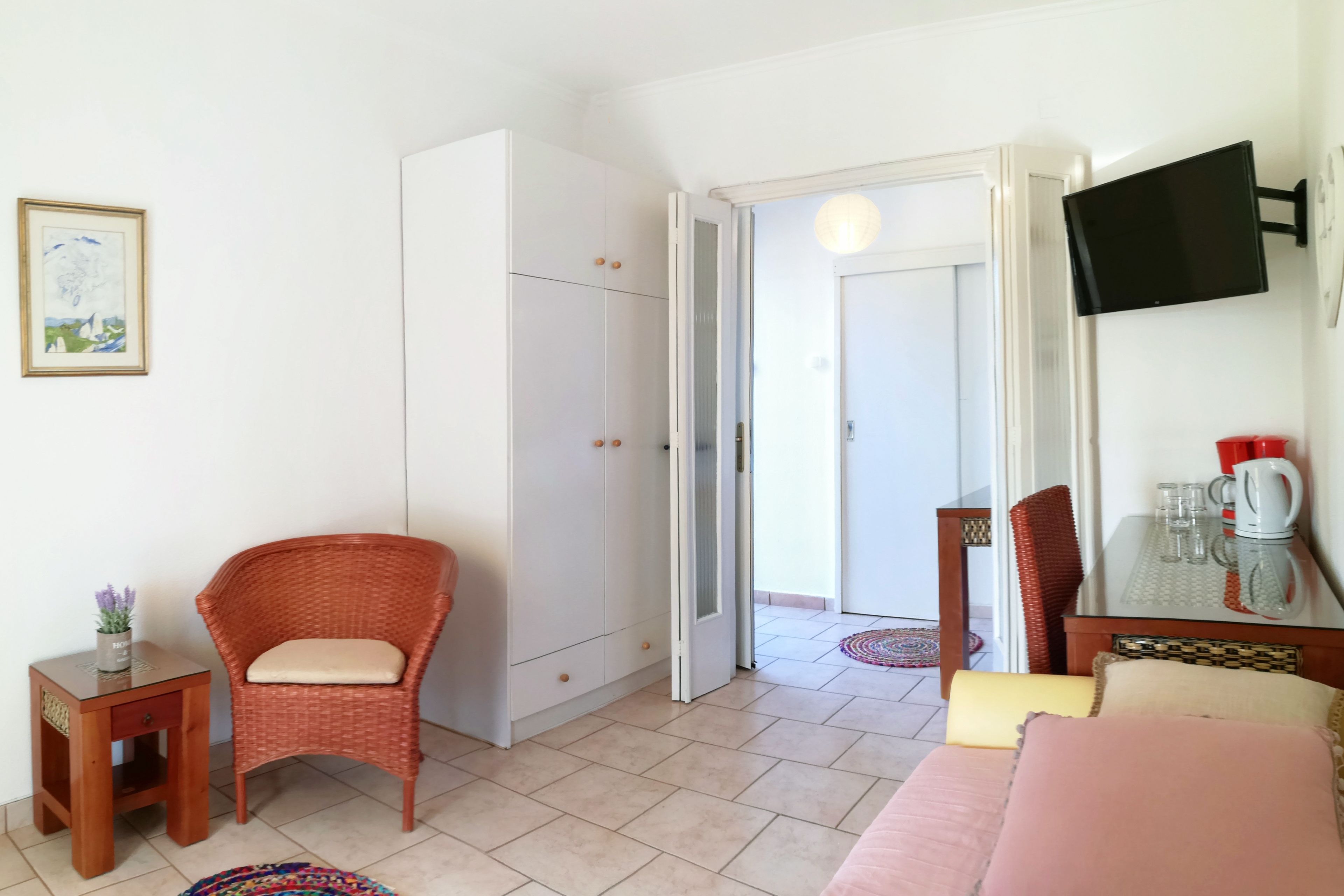 Une pièce comprenant un lit, une chaise, une petite table, une armoire et un téléviseur fixé au mur.