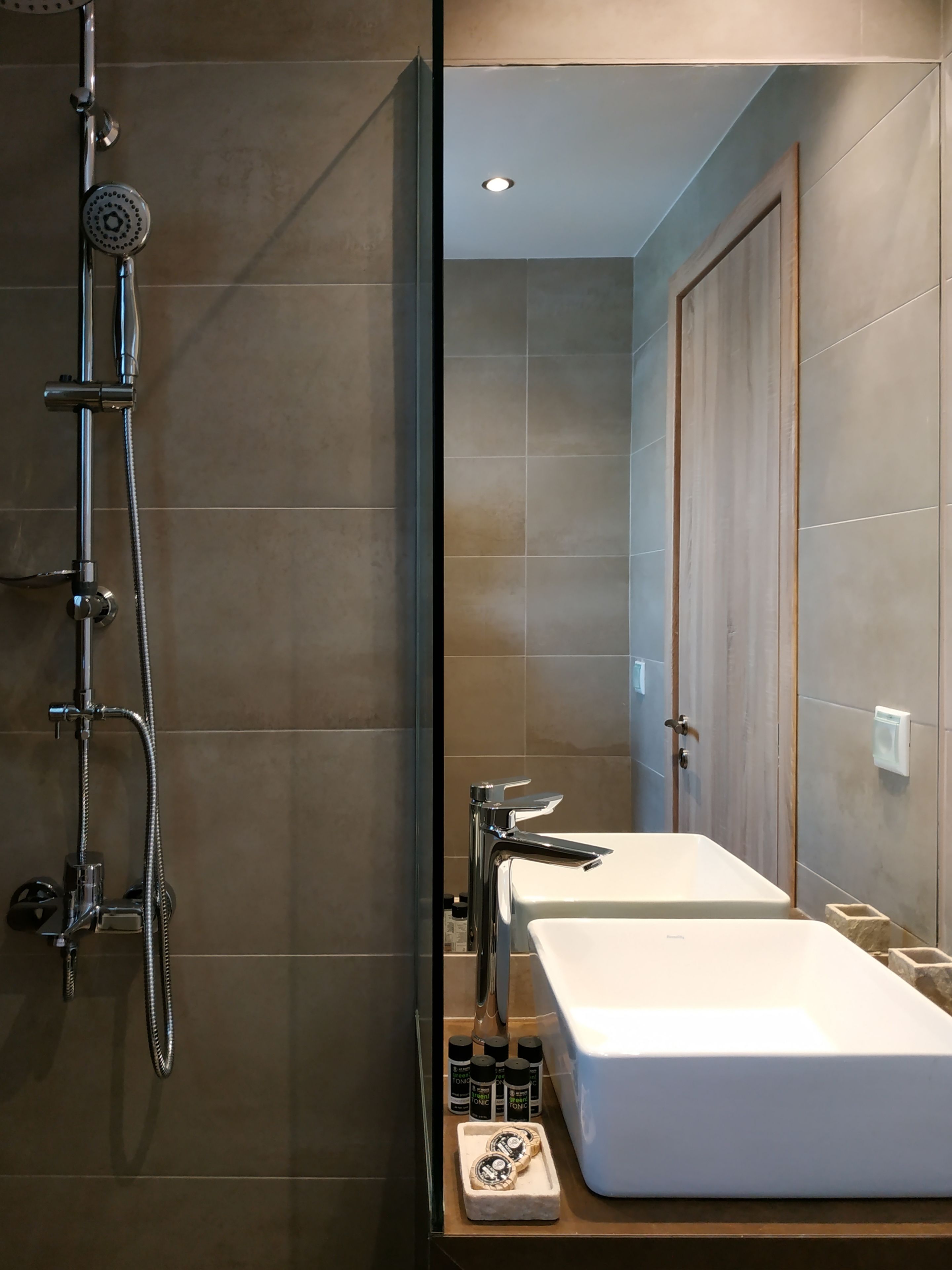 A modern bathroom with a shower, two sinks, and a mirror.