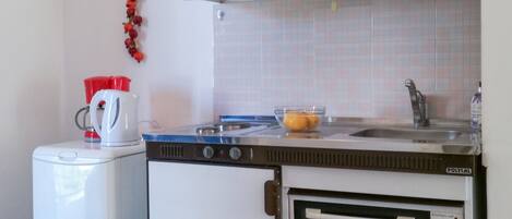 Una cucina compatta con frigorifero bianco, fornello e forno.
