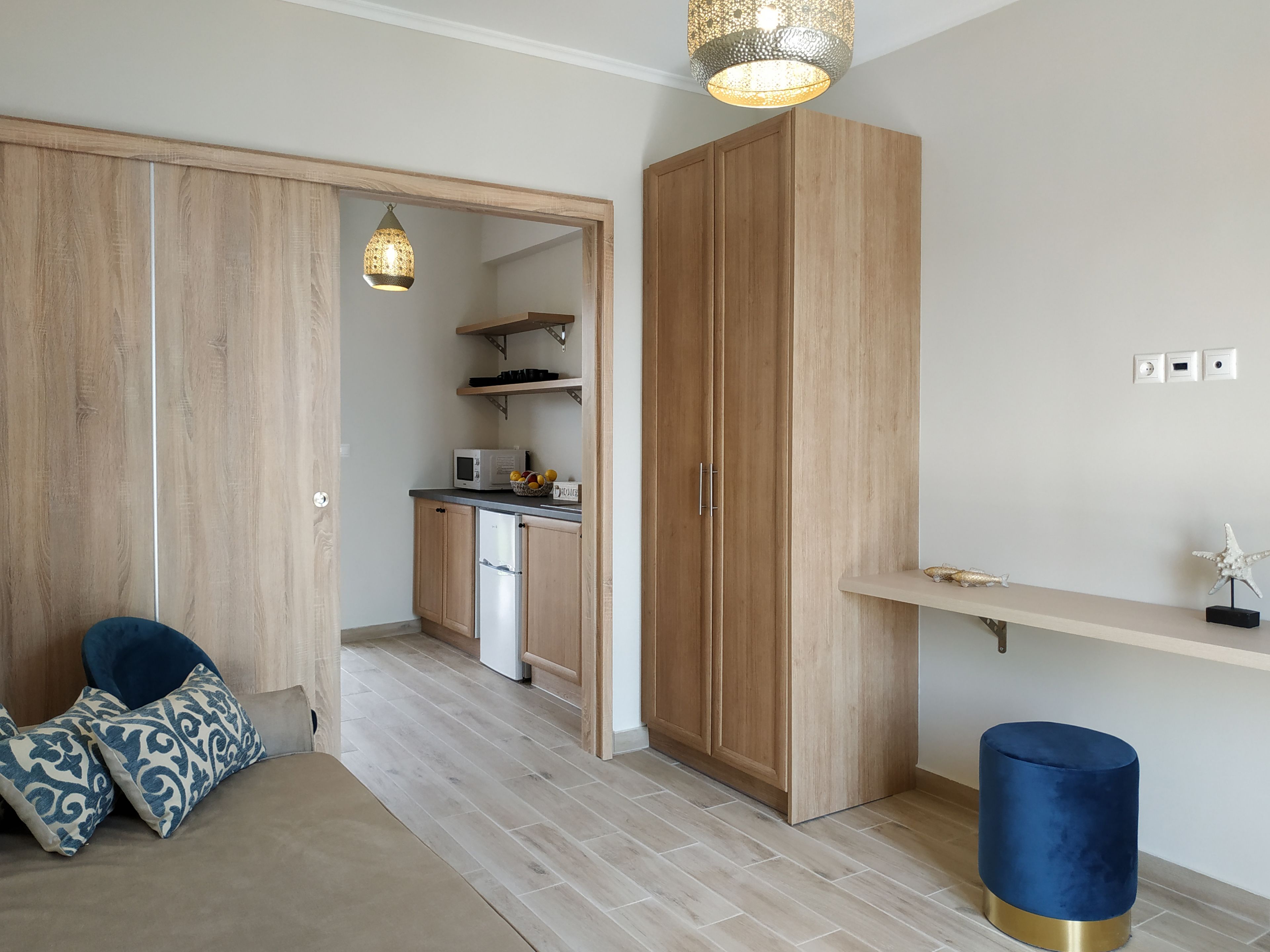 A compact kitchen with wooden cabinets, a microwave, and a fruit bowl.