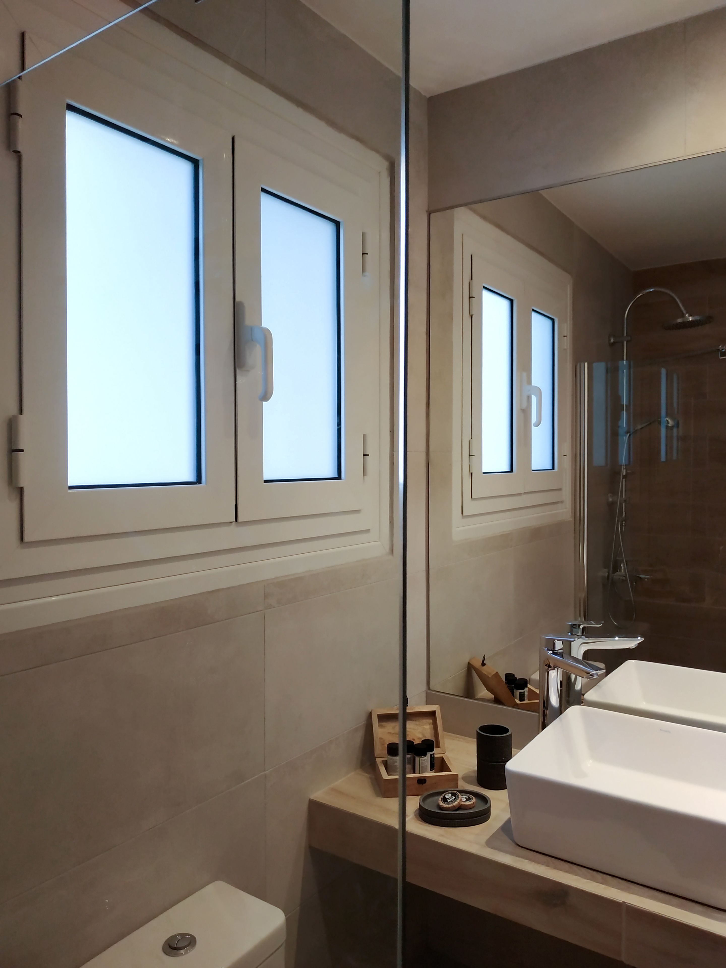 Une salle de bain moderne avec une douche à parois de verre, un lavabo blanc et un miroir qui reflète la pièce.