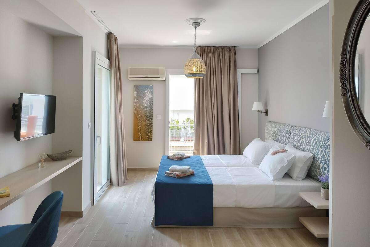 A hotel room with a bed, bedside table, TV, and a window with curtains.