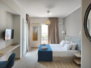 A hotel room with a bed, bedside table, TV, and a window with curtains. - Lilly Apartments (Vari-Voula-Vouliagmeni)