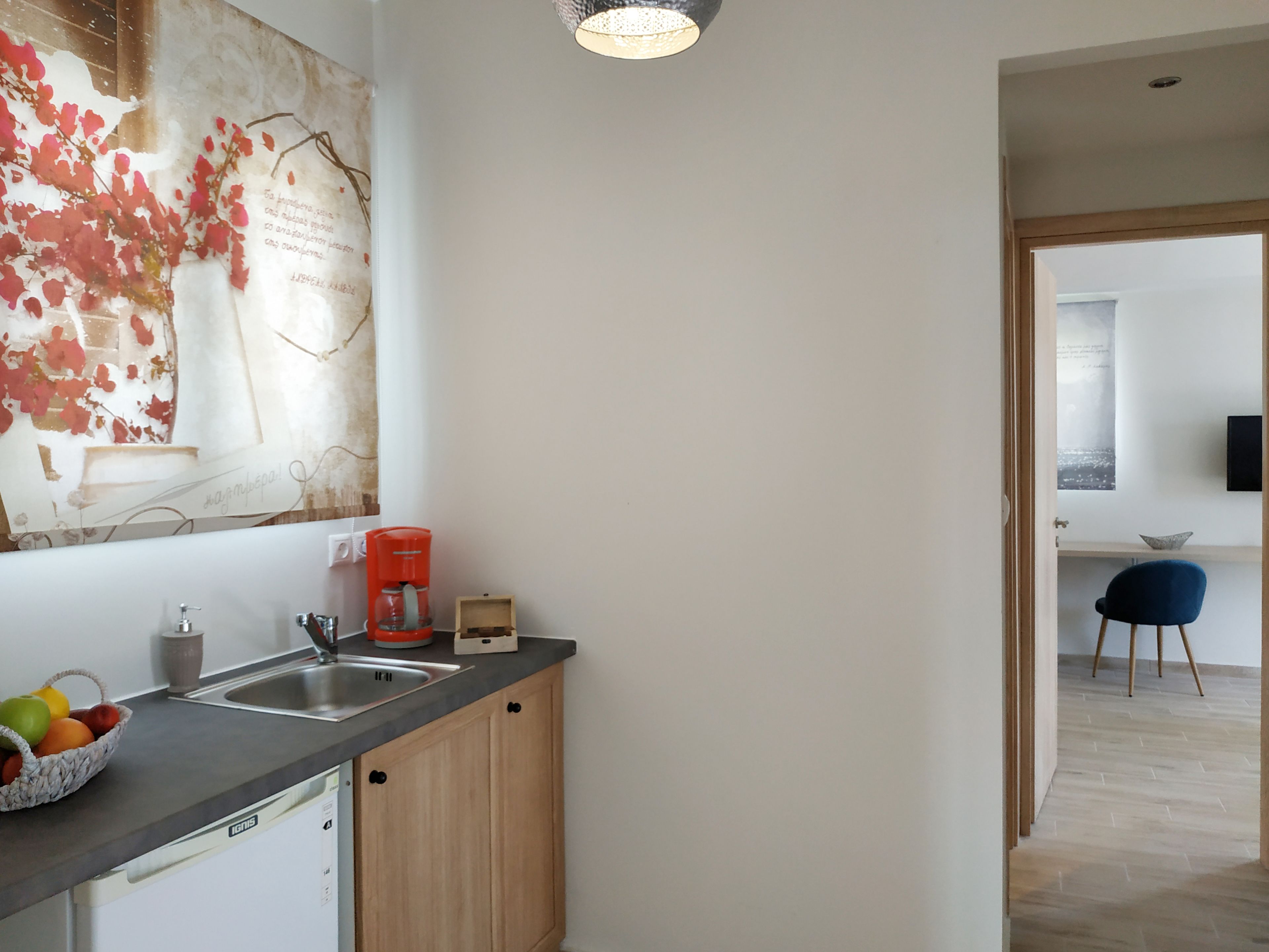 A modern kitchen with a large window, a coffee machine, and a fruit basket on the counter.