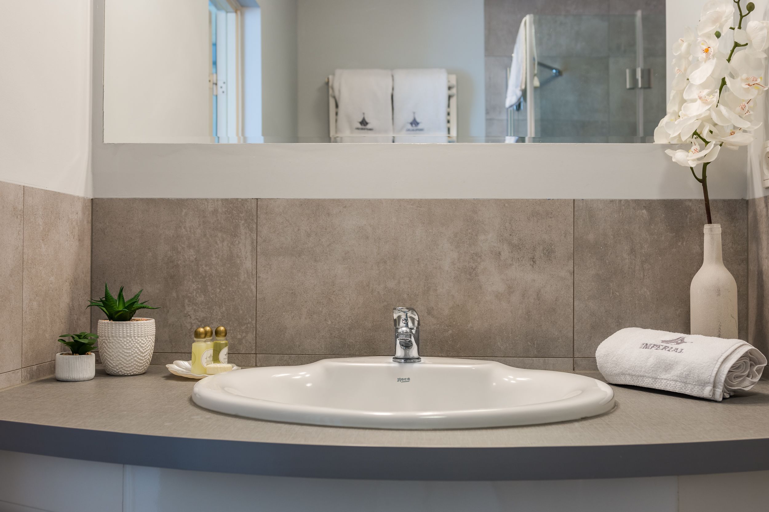 Une salle de bain avec un lavabo blanc, un miroir au-dessus et une serviette posée sur le comptoir.