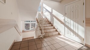 Eine Treppe führt zu einer Zwischenebene mit einer Tür und einem Fenster.