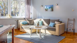 Ein Wohnzimmer mit Sofa, Couchtisch, einer Leiter und einem Fenster mit Vorhängen.