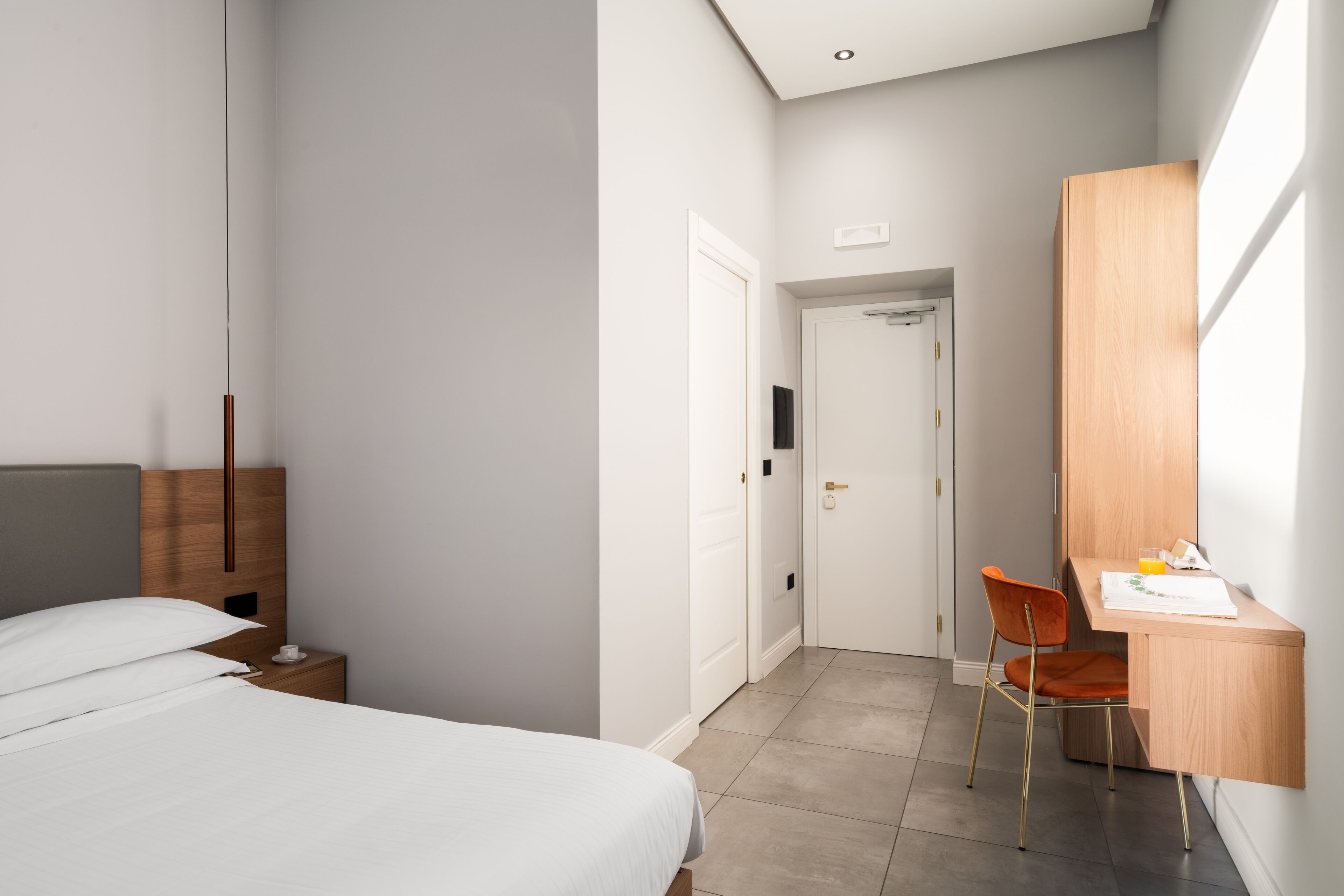 A modern hotel room with a bed, a desk, and a chair.