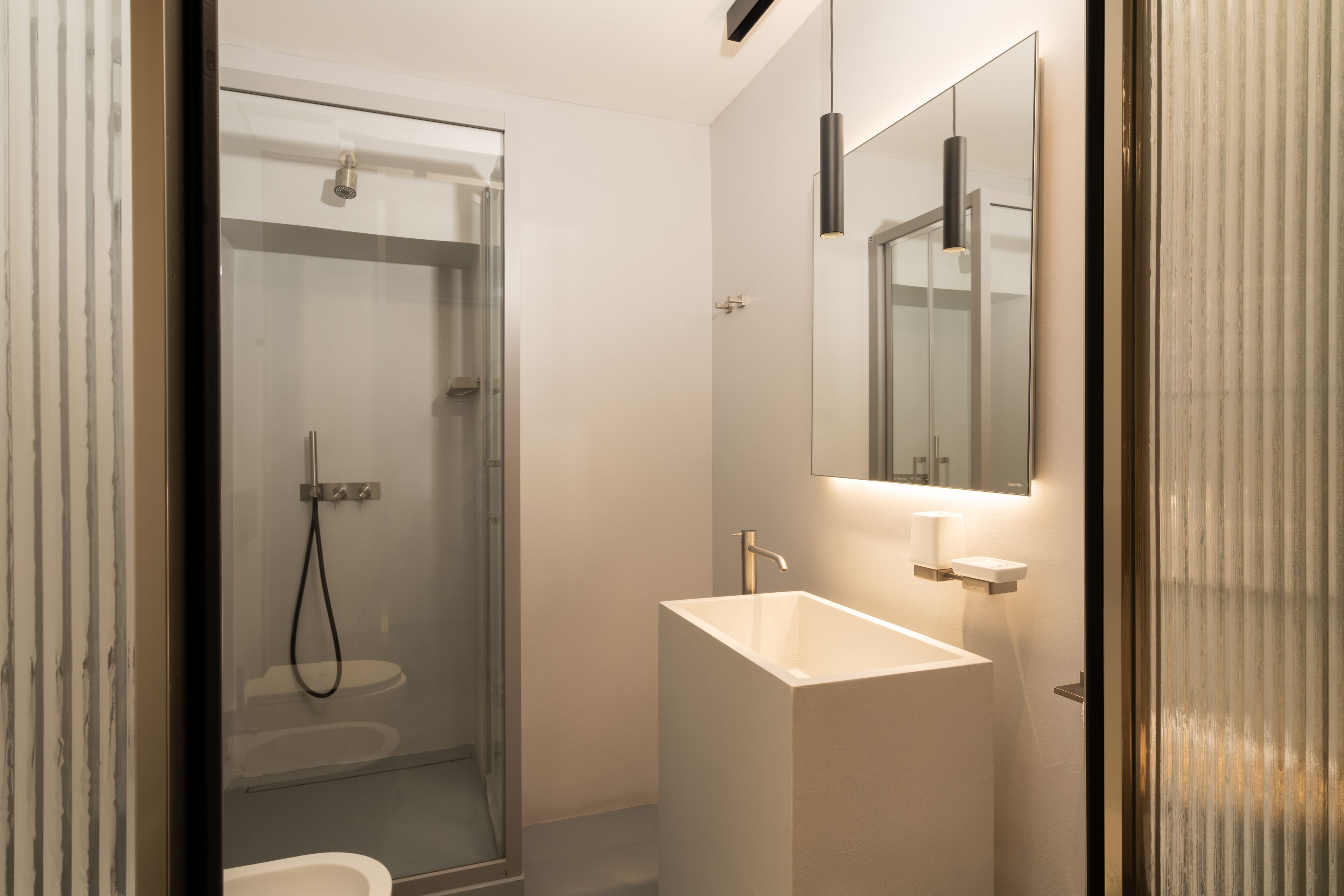 A modern bathroom with a glass-enclosed shower, a white sink, and a mirror above the sink.