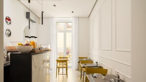 A modern dining area with a kitchen counter, yellow chairs, and a view of the balcony. - The Grey (Naples)