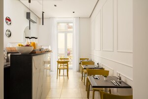 A modern dining area with a kitchen counter, yellow chairs, and a view of the balcony.