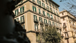 A multi-story building with balconies and green shutters. - The Grey (Naples)