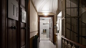 A hallway with wooden doors, a potted plant, and a sign reading "THE GPE". - The Grey (Naples)