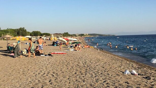 A beach with people sunbathing and swimming, umbrellas, and beach chairs. - Anatolia Hotel Ozdere (Menderes)
