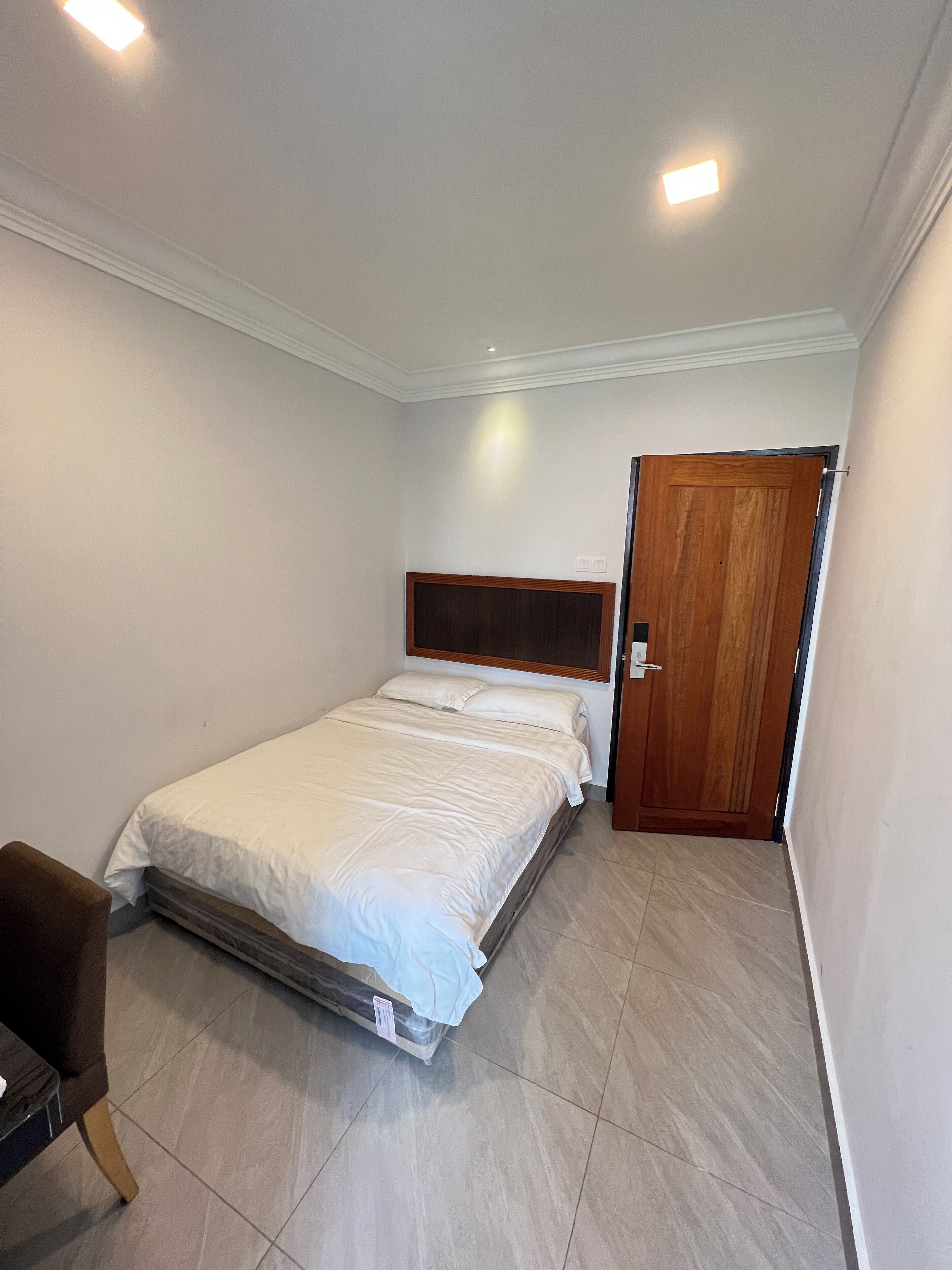 Un dormitorio con cama, puerta de madera y una mesita.