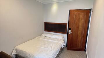 A bedroom with a bed, a wooden door, and a small table.