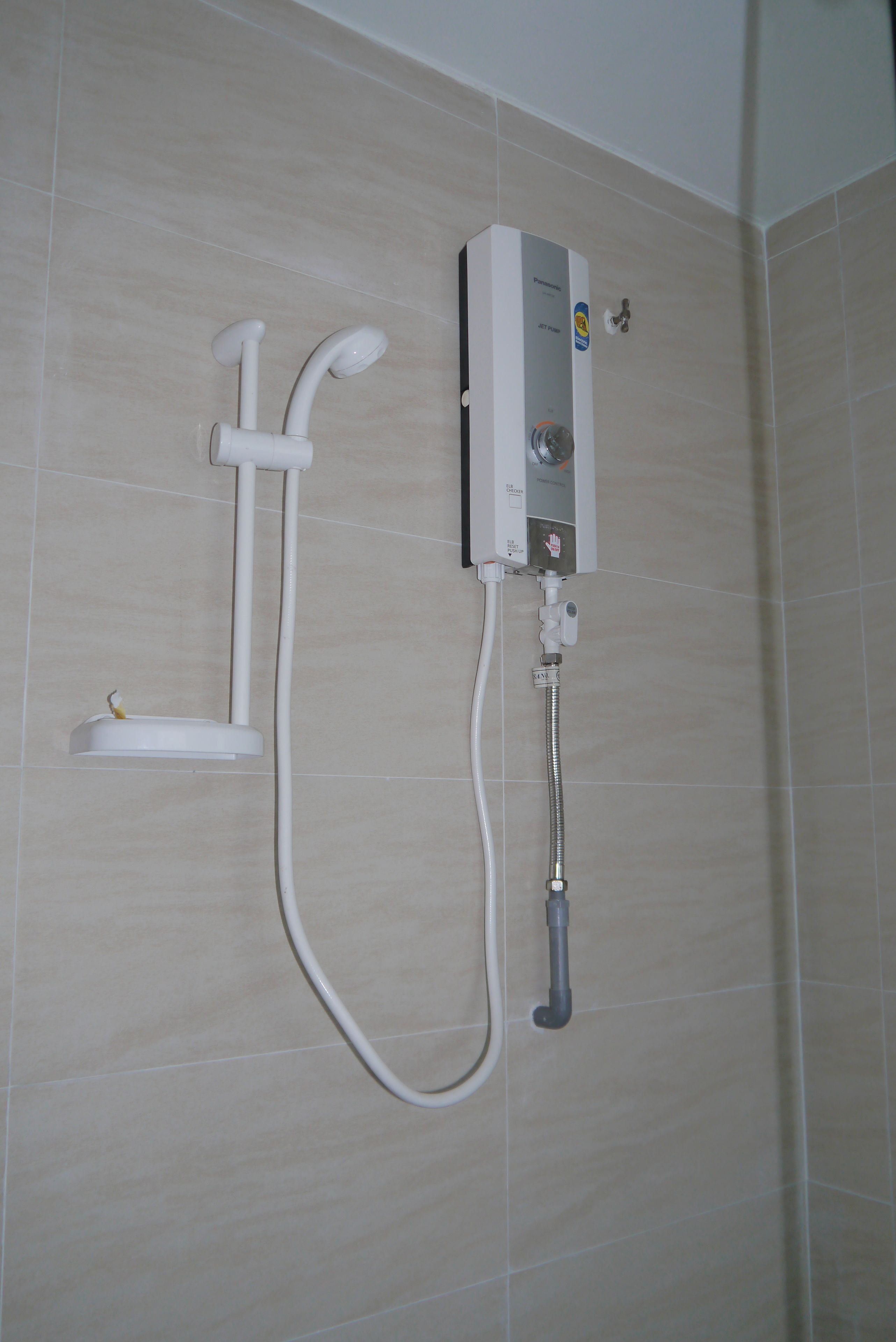 A wall-mounted shower unit with a control panel, a handheld showerhead, and a flexible hose.