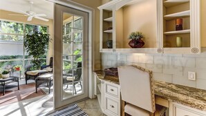 A kitchen with a large window, a ceiling fan, and a dining area with wicker furniture. - Exclusive Gated Villas at Summer Beach, Short Walk to the Beach by RedAwning (Fernandina Beach)