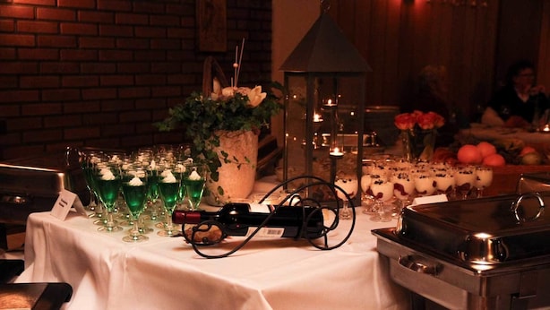Een gedekte tafel met groene cocktails, een fles wijn en glazen voor desserts.