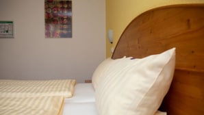 Een slaapkamer met twee bedden, een houten hoofdbord en een muur met een kleurrijk poster.