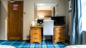 Habitación de hotel con un escritorio de madera, una silla, una cama y un piso a cuadros azules.