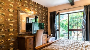 Una habitación de hotel con una cama grande, un tocador de madera, un televisor y una ventana con cortinas.
