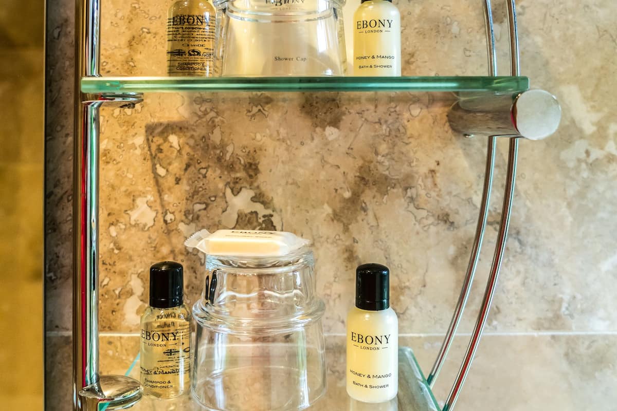 A bathroom shelf with various toiletries including a shower cap, a bottle of lotion, and a glass jar.