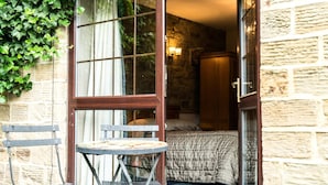 Una habitación con una cama, una puerta de madera y un ventanal con cortinas.