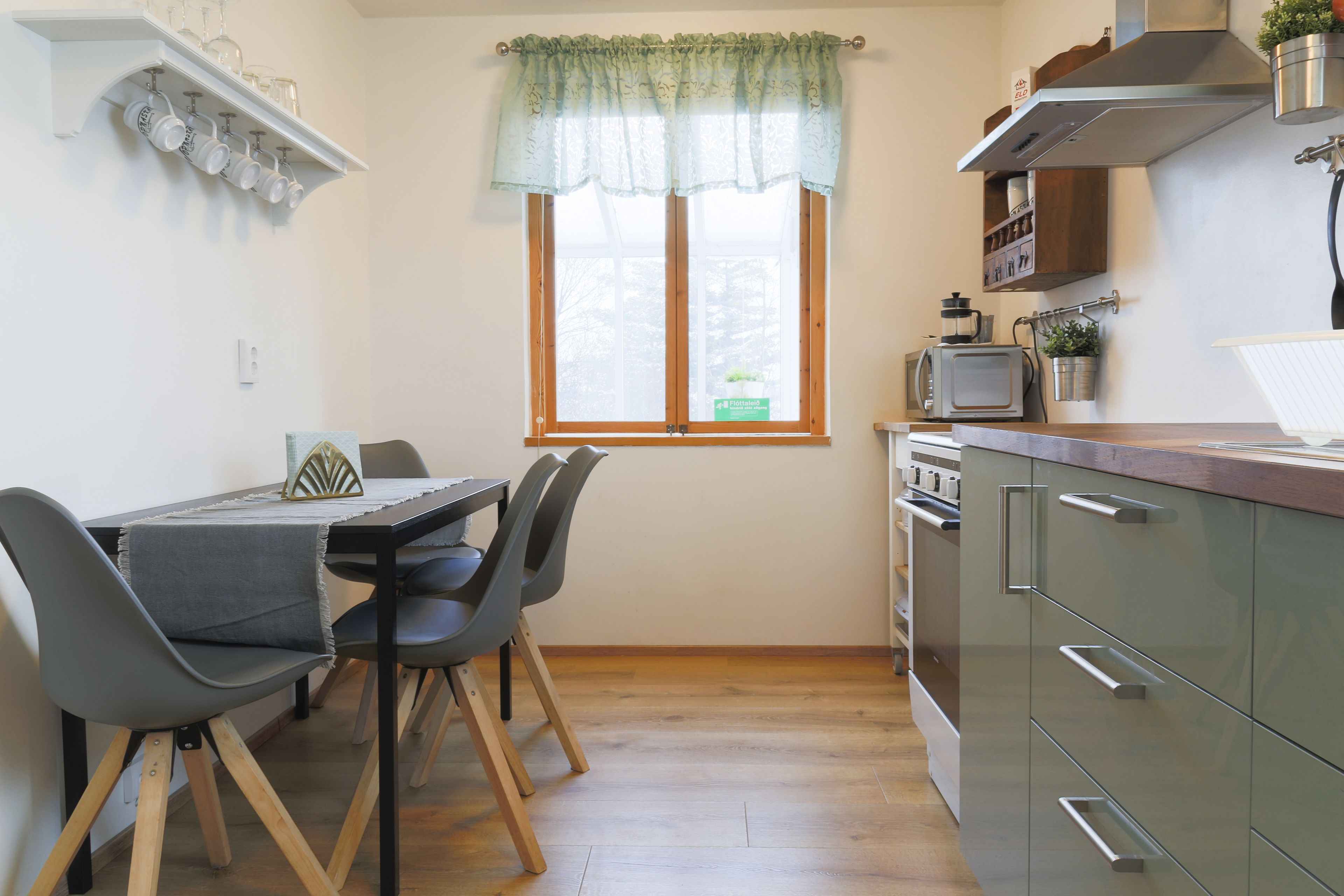 A compact kitchen with a dining table, chairs, and a window with curtains.