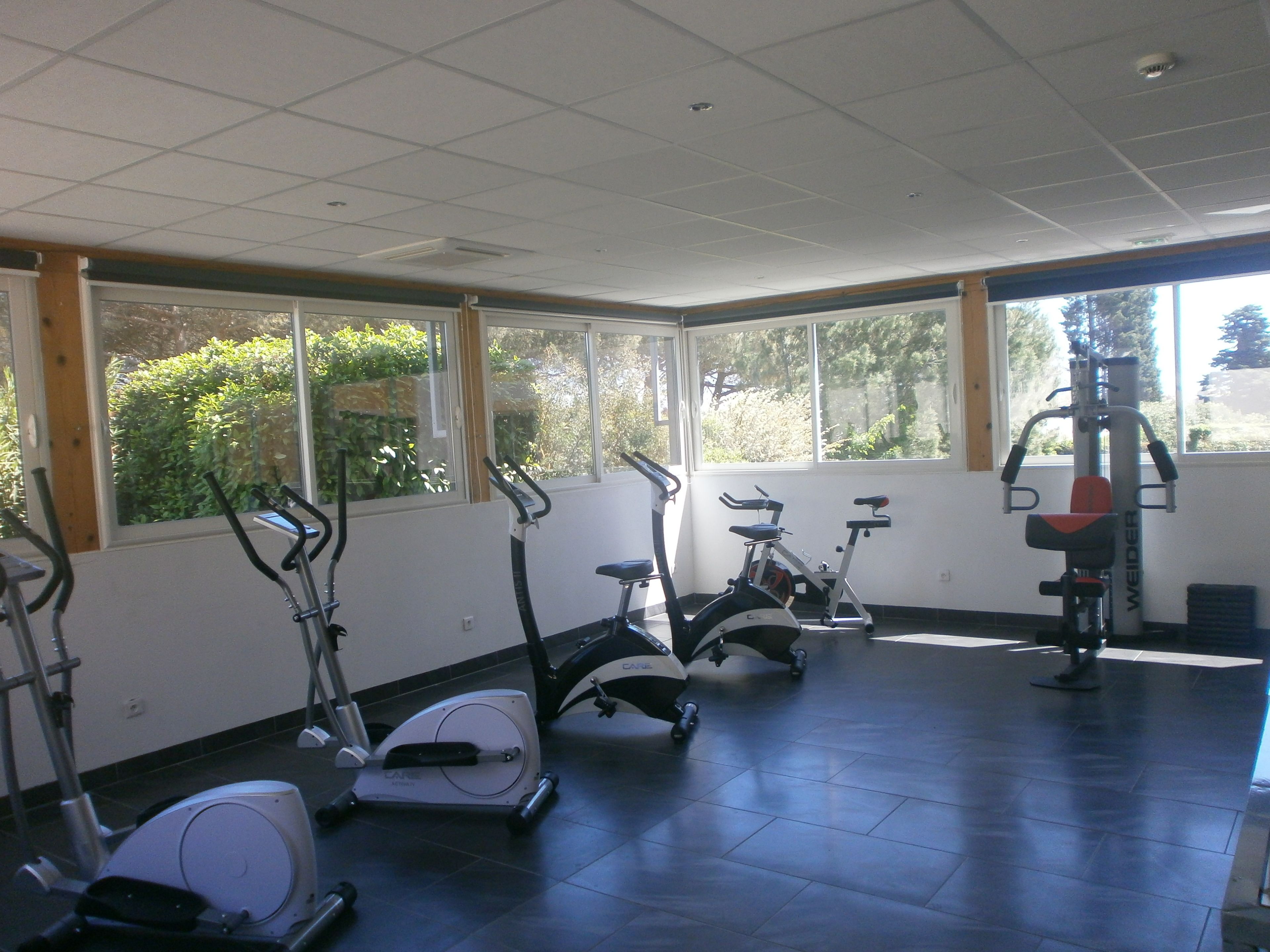 Uma academia com bicicletas ergométricas, esteira e máquina de musculação.
