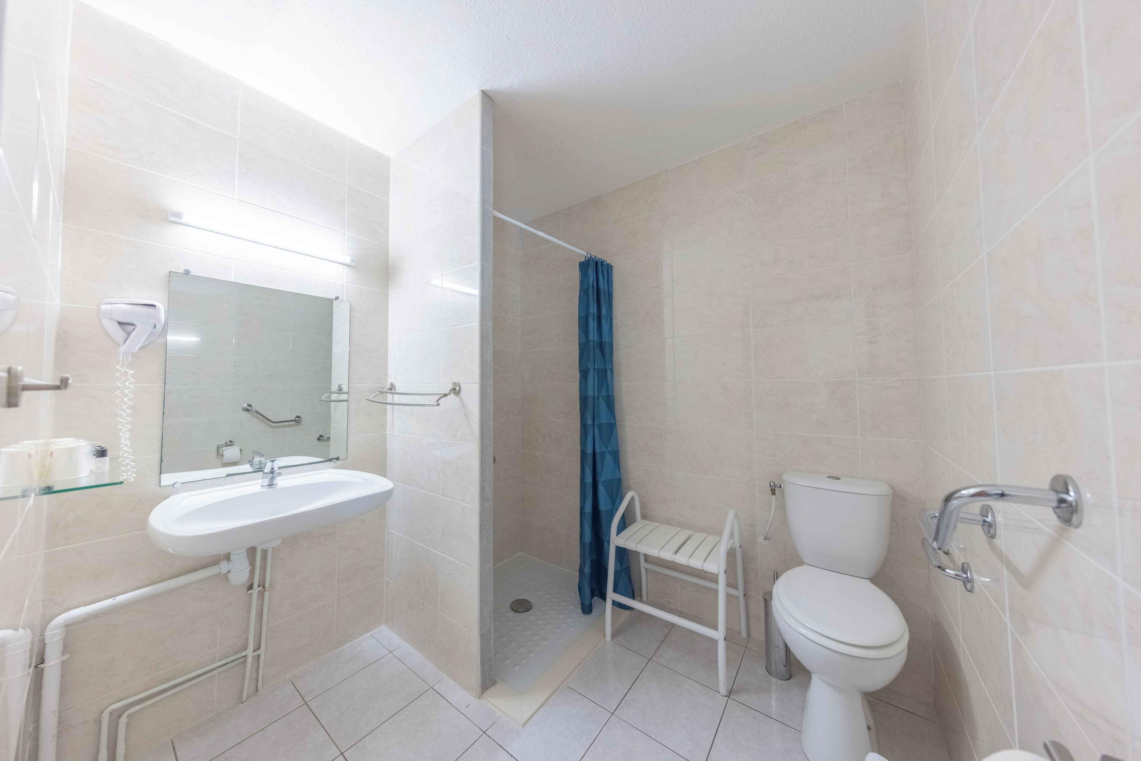 A bathroom with a white sink, mirror, toilet, and shower area.
