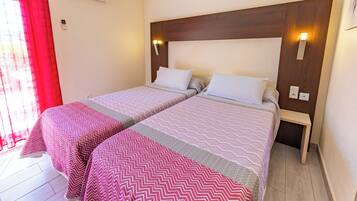 A double room with two beds, each with patterned bedding and bedside tables with lamps.