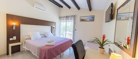 A bedroom with a bed, bedside table, lamp, potted plant, and a window with curtains.